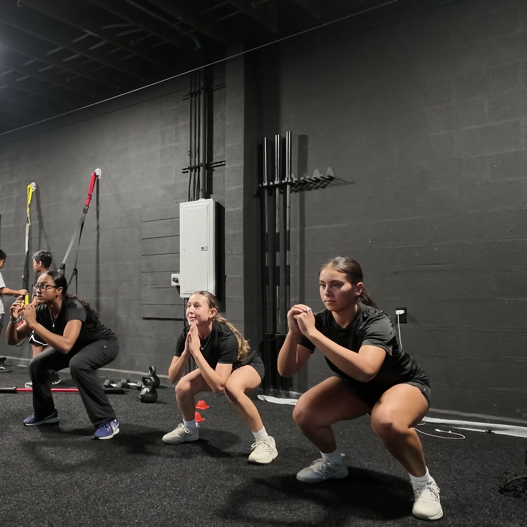 Three athletes squatting side by side at Level Up