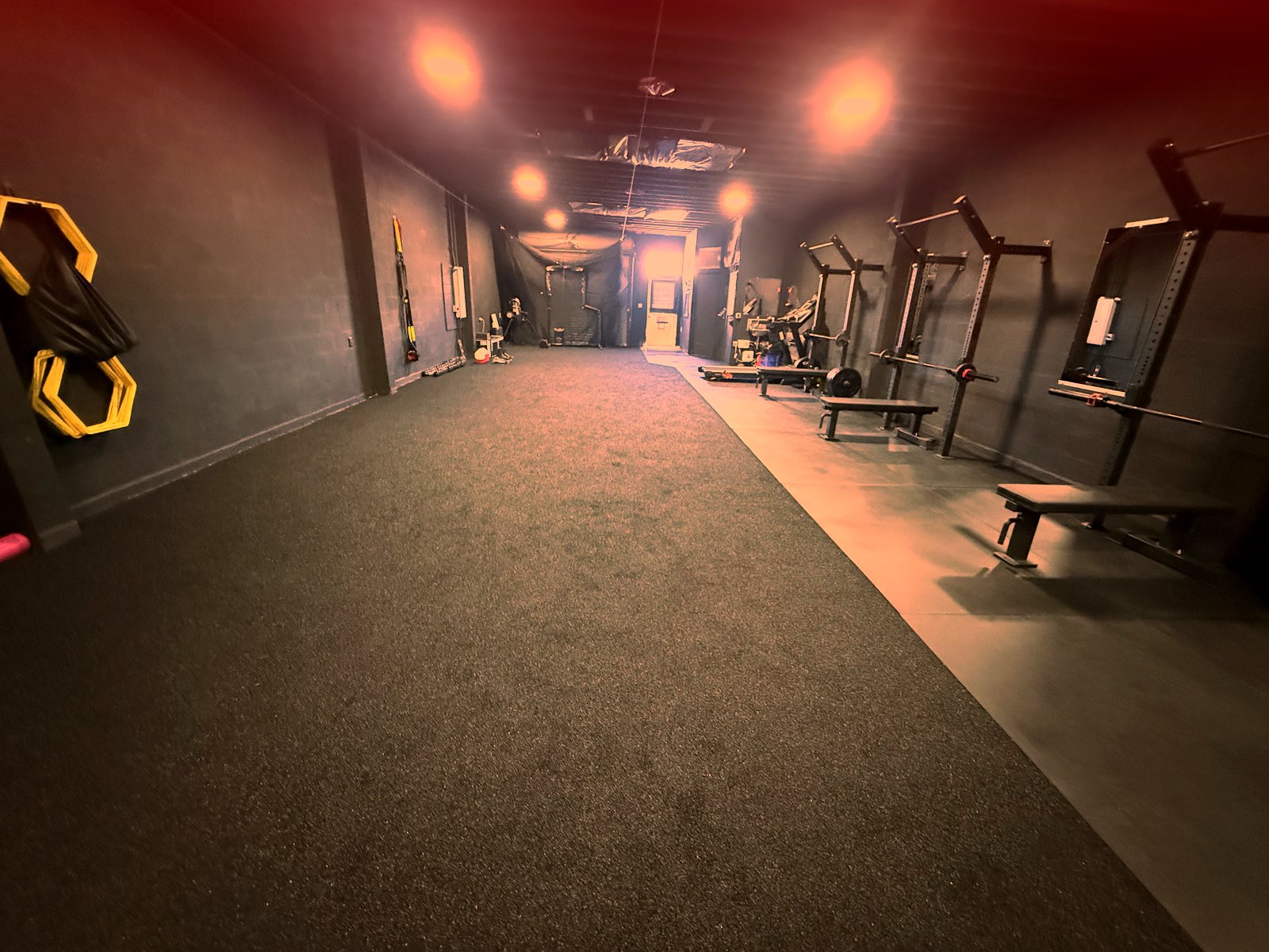 Inside the new Level Up facility — turf runway, squat racks, and benches under the lights