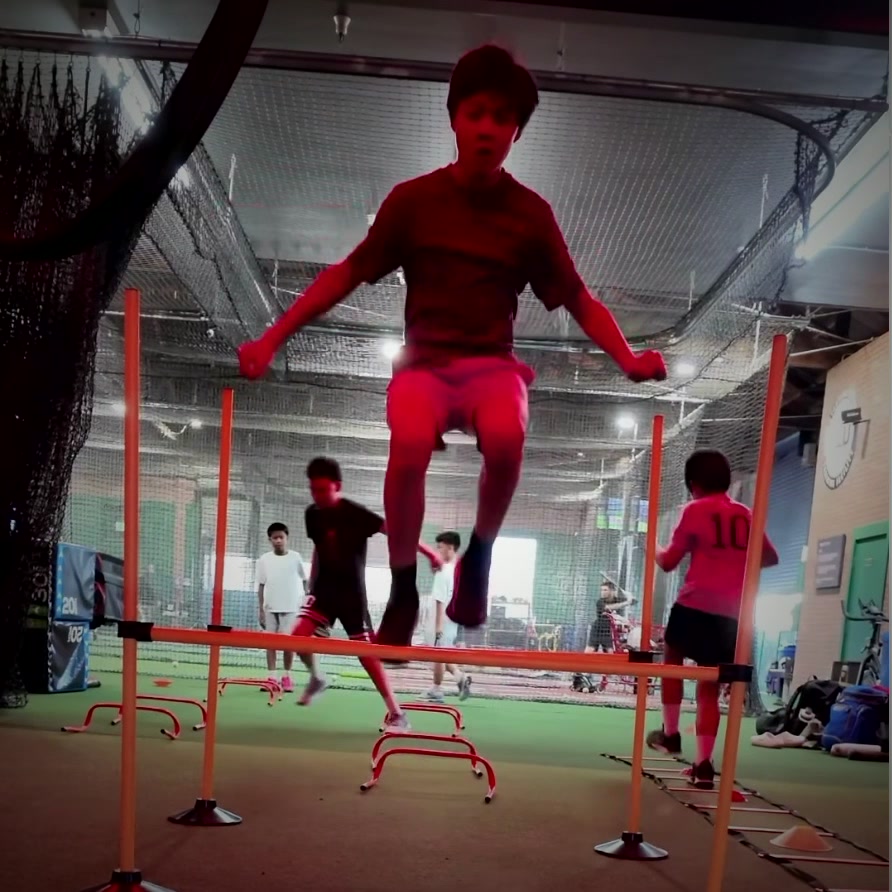 Young athlete mid-air over a hurdle during a Level Up training session